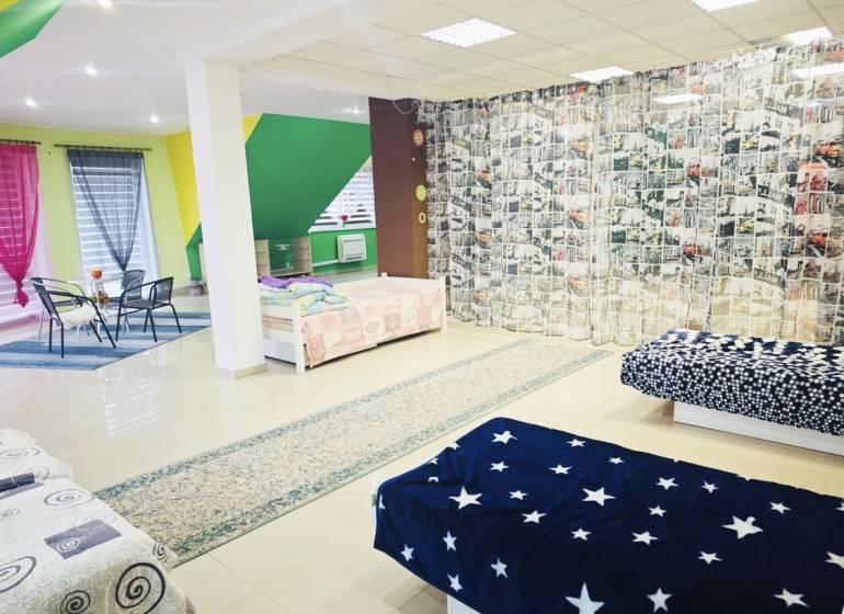 A spacious room in a family house with colorful elements and various bedspreads.