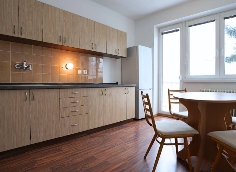 A kitchen in a 3-room apartment with a wooden decor floor and a dining table.