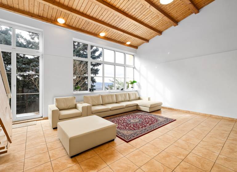 Living room in a family house with a cream sofa, large windows, and ceramic tiles.