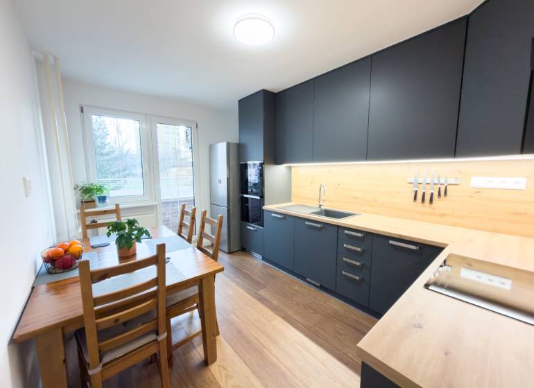 A kitchen in a 4-room apartment with a wooden decor floor and a dining table.