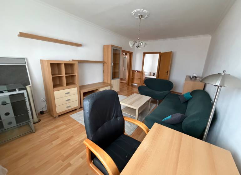 Living room in a three-room apartment with a wooden decor floor, furniture, and a sofa.