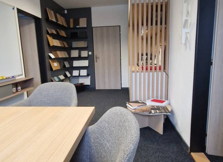 Offices with carpet flooring, a wooden desk, and a bookshelf.