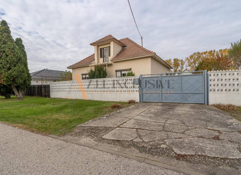 A family house in Veľké Dvorníky with a large garden, trees, and a concrete walkway.