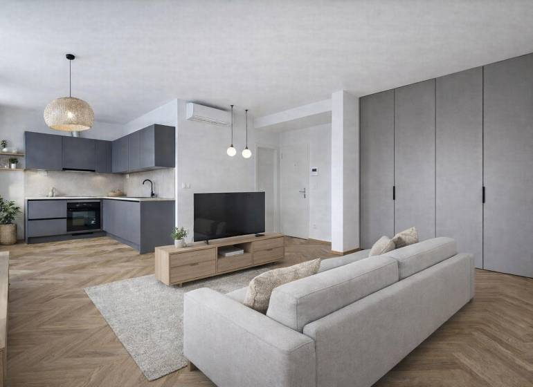 A kitchen in a studio apartment with a wood-patterned floor and gray cabinets.