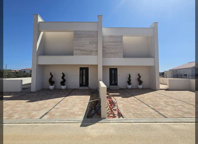A family house on Mulo Street in Vrsi with a paved walkway and decorative plants.