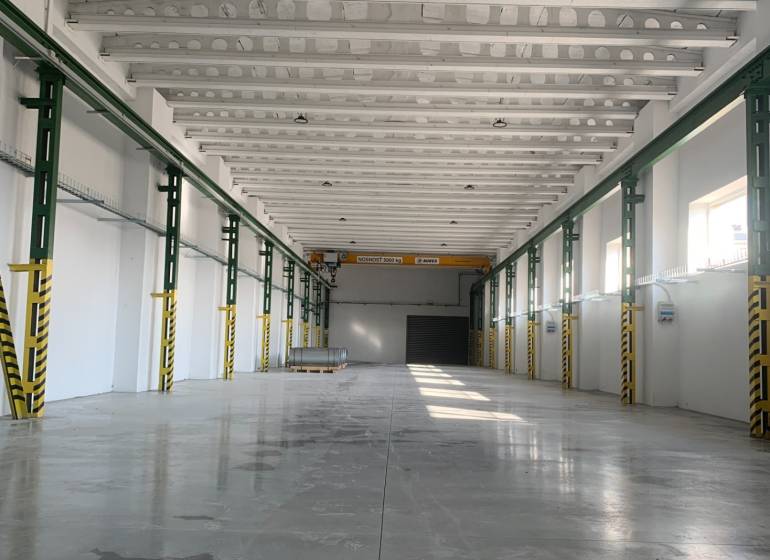 Spacious interior of a warehouse and hall with a reinforced concrete ceiling and smooth concrete floor.