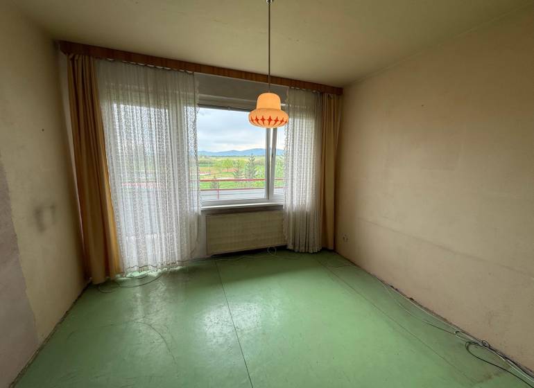 A room with a green floor and a large window in a 3-room apartment.