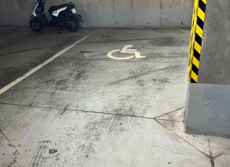 Handicapped parking space with a parked scooter in the garage.