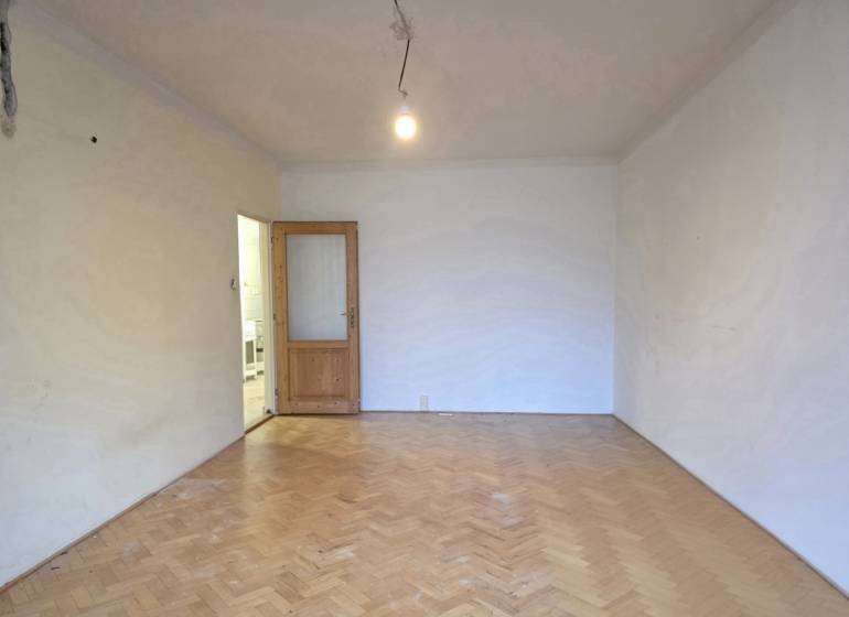 A room in a 2-room apartment with a wooden decor floor and open doors.