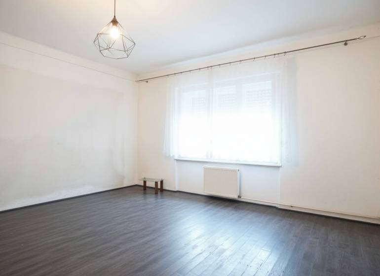 A room in a family house with a wood-patterned floor and a large window.