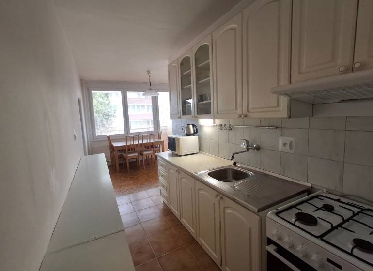 A kitchen in a 3-room apartment with a gas stove and a dining table.