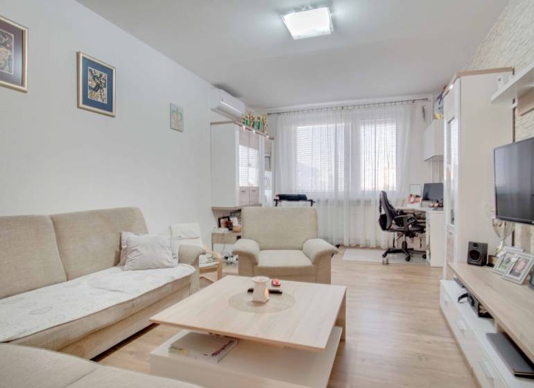 Living room with a sofa and TV in a 3-room apartment, floor with wooden decor.