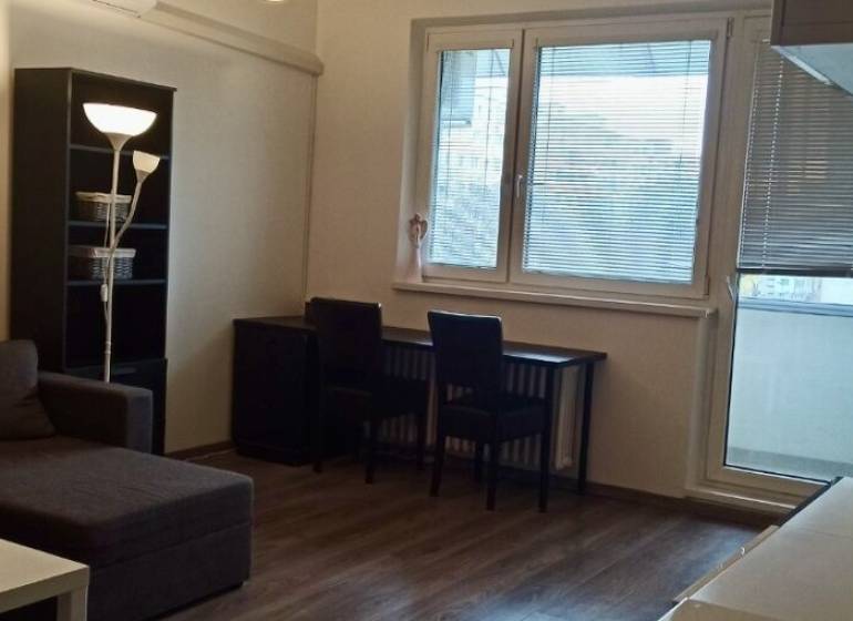 Living room in a two-room apartment with a corner sofa and a floor with a wooden decor.