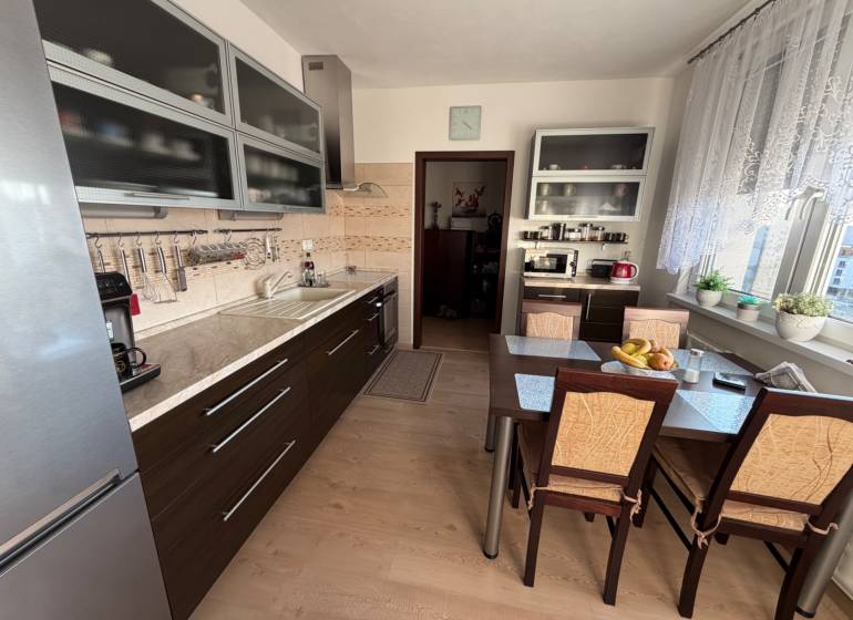 A kitchen in a 3-room apartment with a kitchen unit and a table, floor with wooden decor.