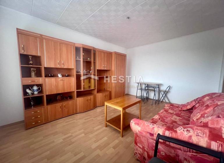 A living room in a three-room apartment with a red sofa and a wooden wall unit.