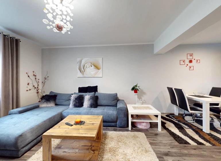 Living room in a family house with a blue sofa, dining table, and floor with a wooden decor.