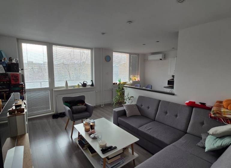 Living room of a 3-room apartment with a sofa, coffee table, and wooden decor flooring.