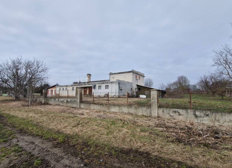 Production premises in Lesenice with a fenced plot, next to a dirt road and trees.