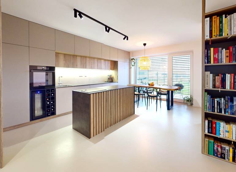 Open kitchen with dining table and bookshelf in a family house.