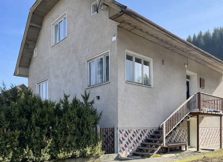 A family house in Terchová with large windows, a staircase, and a well-maintained front garden.