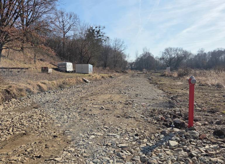 Lands - housing in Haniska, a rocky road between trees and a container.