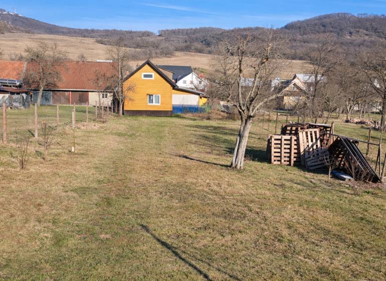 The yard of the cottage in Kráľovce Krnišov with fruit trees and mountains in the background.