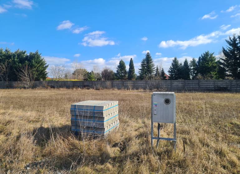 Building plot in Nové Zámky with concrete blocks and an instrument box, surrounded by greenery.