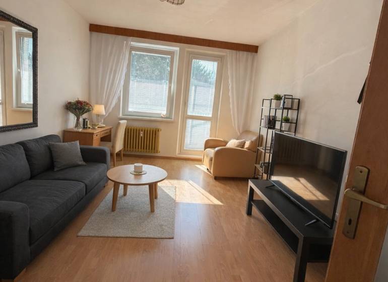 Living room in a three-room apartment with a wooden decor floor and comfortable furniture.