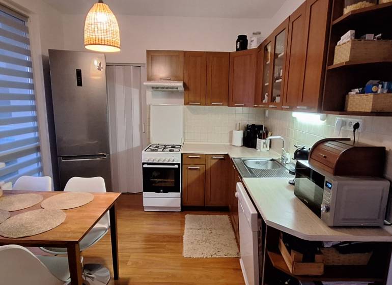 A kitchen with a wooden decor floor, dining table, appliances, bright interior in a 4-room apartment.