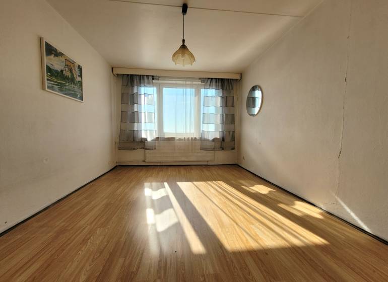 A bright room with a large window, curtains, and a wooden decor floor in a 2-room apartment.
