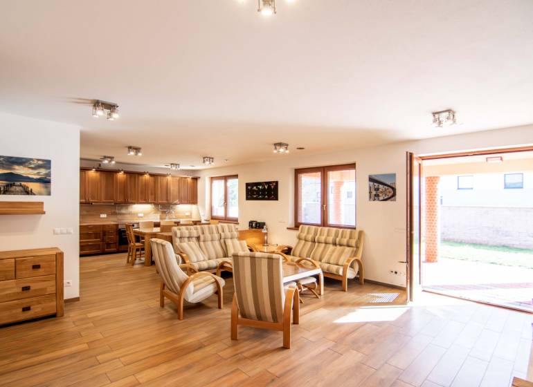 Living room with dining area and kitchen, wooden decor flooring, family house.