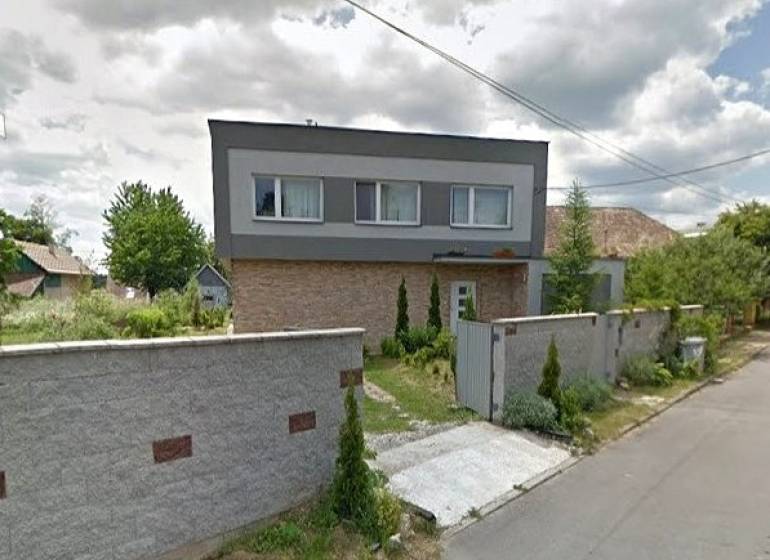 A family house in Bystrička with a landscaped garden and a high fence along the street.