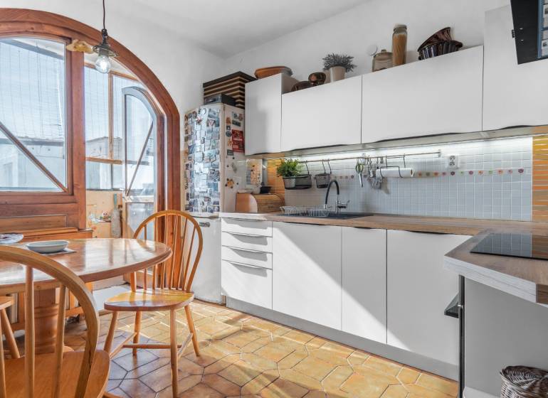 A kitchen in a 4-room apartment with wooden decor, an arched window, and a dining table.