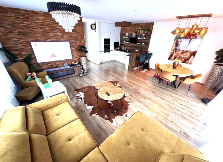 Living room with a sofa, dining table, and wooden decor flooring in a family house.