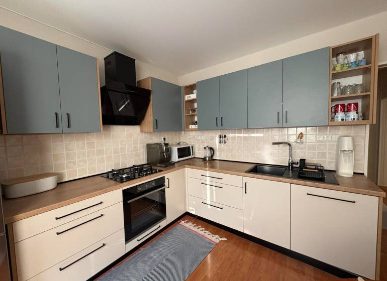 A kitchen in a 3-room apartment with a wooden decor floor and cooking equipment.