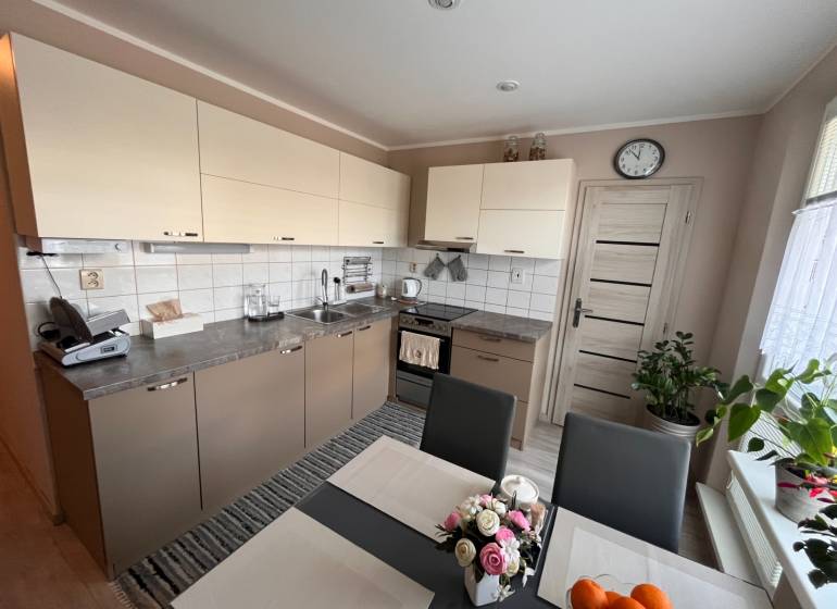 A kitchen in a 3-room apartment with light cabinets and a dining table.