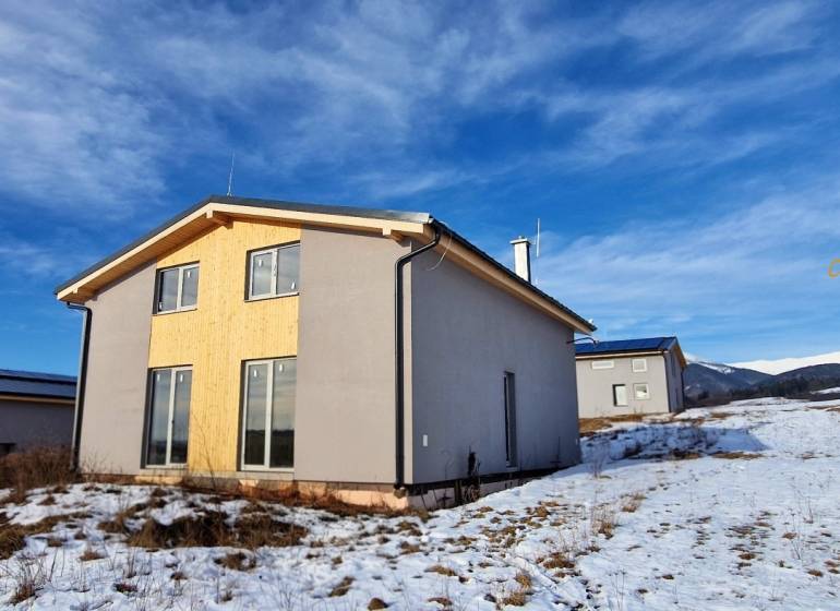 A cottage in Dolná Lehota with wooden cladding, a snowy landscape, and mountains on the horizon.