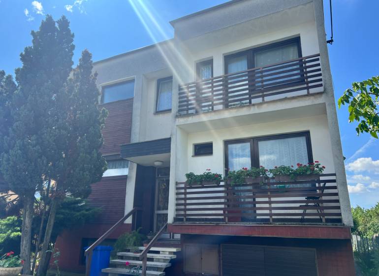 A family house on Tálová Street in Veľké Orvište with two balconies, trees, and a garage.