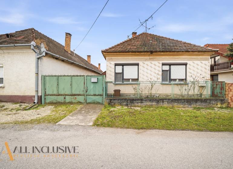 A family house in Topoľníky with a green gate and metal fence, sloped roof.