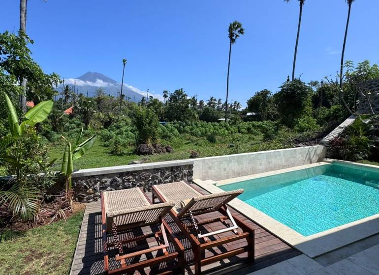 Sunbeds and loungers with a view of greenery on Amed Street, Amed, next to a family house.