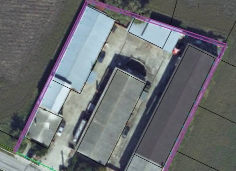 Aerial view of warehouses and halls in Jánovce surrounded by fields.