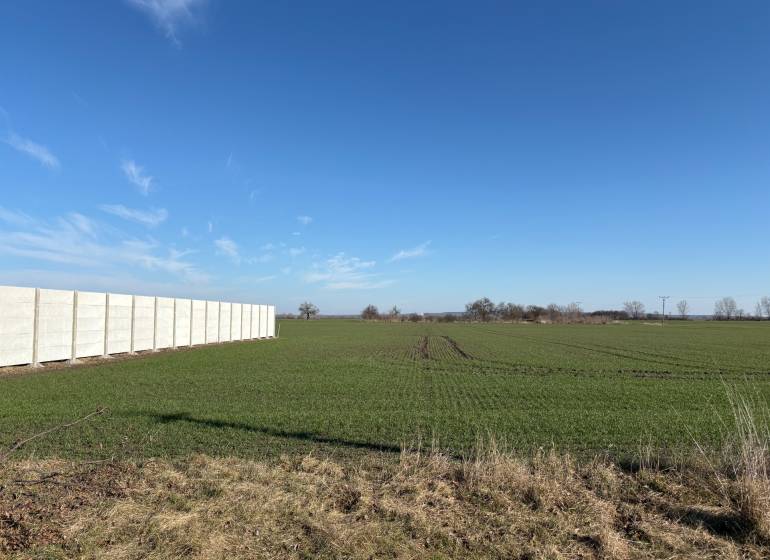 Land - housing in Iža with a green field and a white concrete fence.