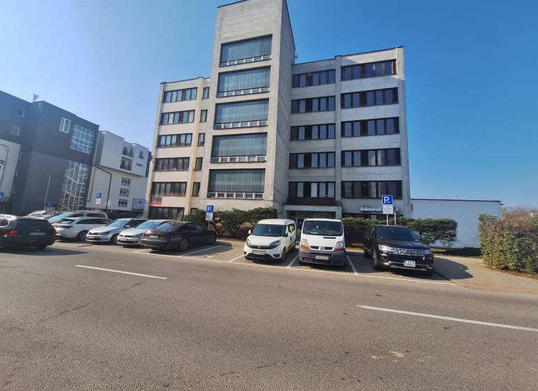 Office building on Tulská Street in the city of Zvolen, with a parking lot and parked cars.