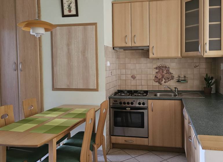 A kitchen in a 3-room apartment with a wooden decor and a dining table with four chairs.