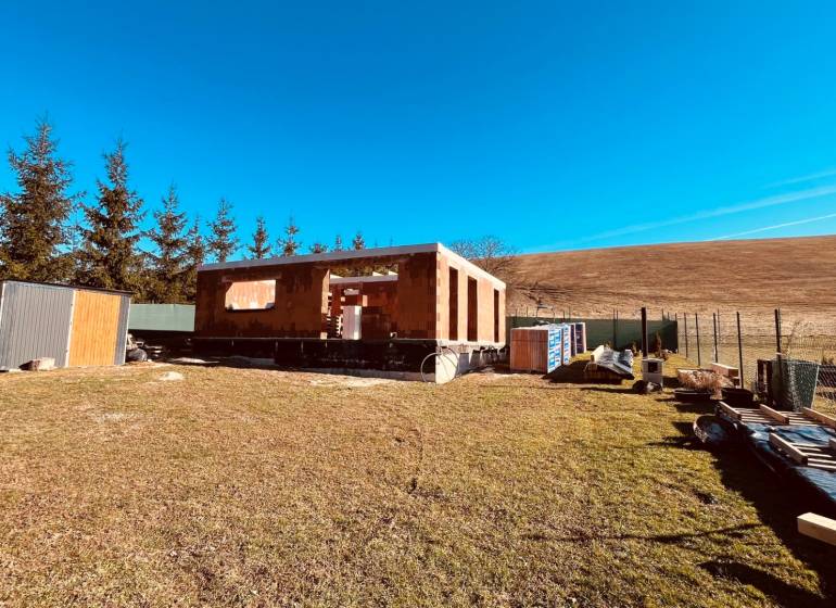 Construction of houses in Prosačov on Prosačová Street surrounded by nature and a clear sky.