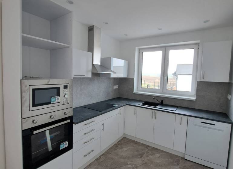 A kitchen in a family house with white cabinets and built-in appliances.