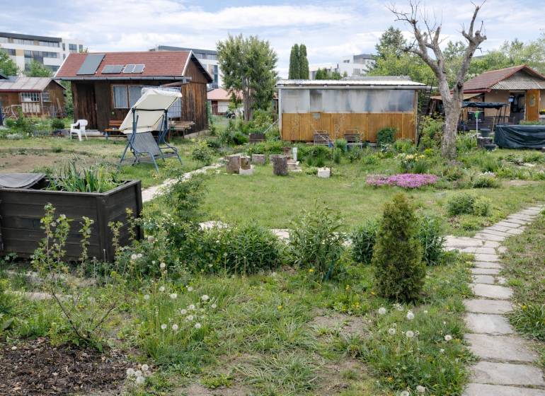 Gardens on Brežný Row in Poprad with cottages, greenery, and a relaxation corner.