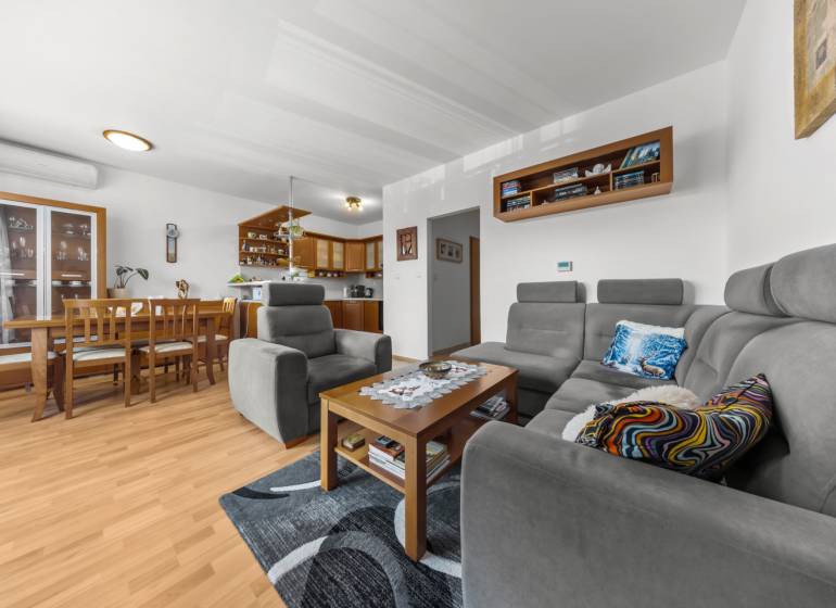 Living room and kitchen with a gray set, wooden furniture, and a floor with a wood decor.