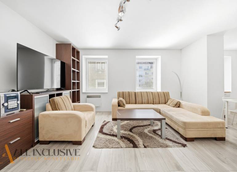 Living room in a three-room apartment with a sofa and a wooden decor floor.