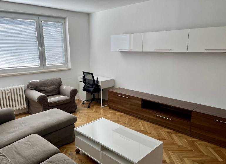 Living room with wood-patterned flooring, sofa, coffee table, and desk.